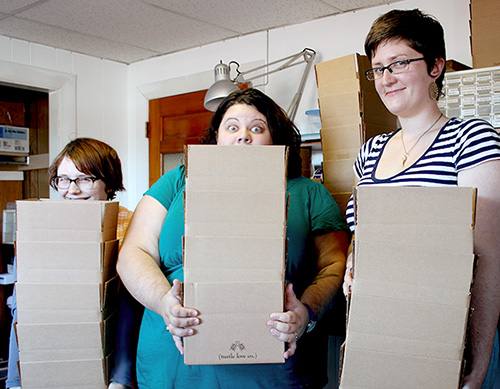 Aubin, Alicia, and Emily holding stack of shipping boxes